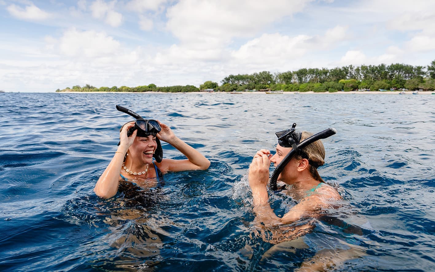 Two travellers snorkelling in the ocean smiling at each other in Gili Trawangan, Indonesia