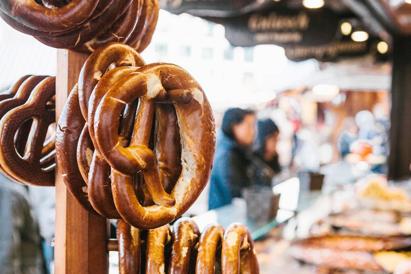 Pretzels hanging on wooden stand at outdoor market stall