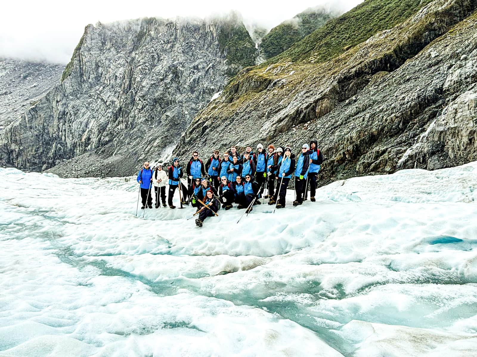 Big group of travellers stood at the edge of a glacier, Franz Josef, New Zealand