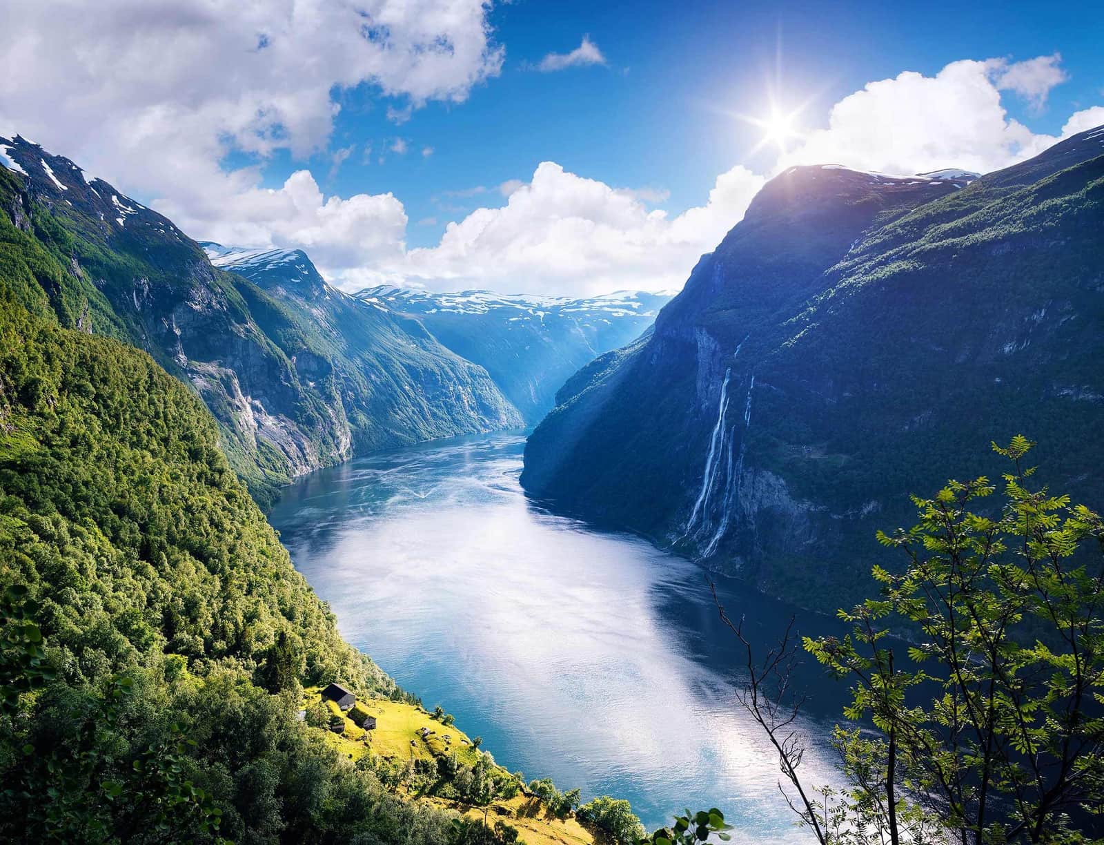 Panoramic view of Geirangerfjord with steep green mountains and waterfall