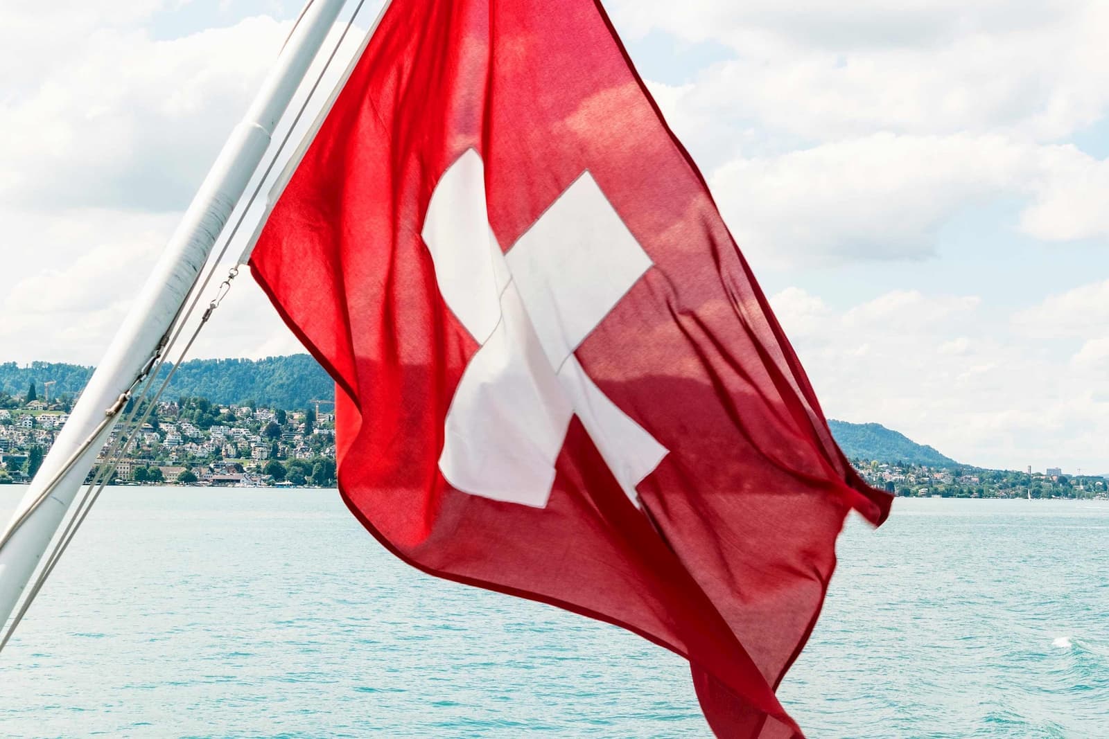 A Swiss flag waving over a lake in Switzerland