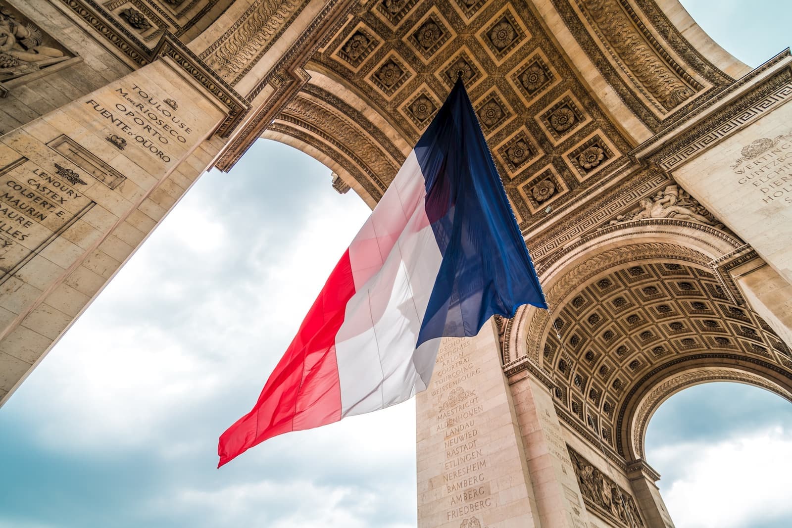 The French flag waving at the Arc de Triomphe monument in Paris, France