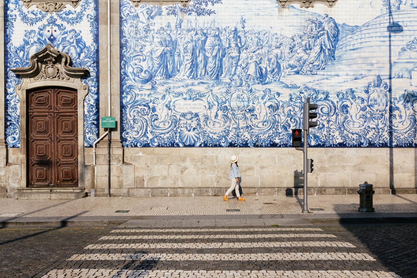 Woman walking past azulejos wall Porto, Portugal