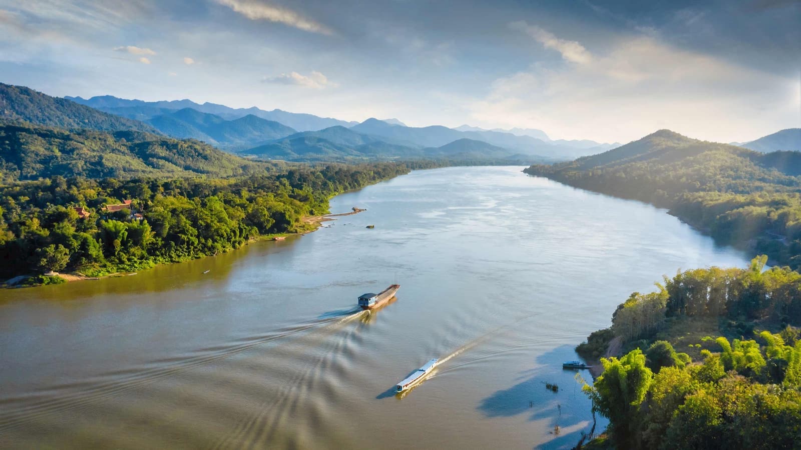 Wide river and mountain with boats gliding downstream in Mekong River, Thailand