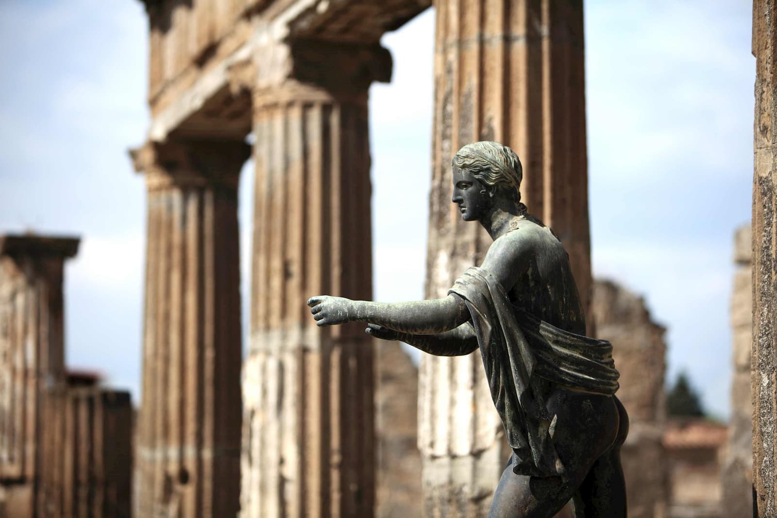 Statue at Temple of Apollo in Pompeii with ancient stone columns and ruins