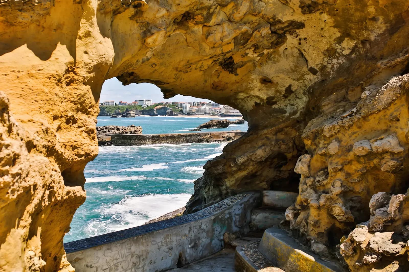 The ocean and coastline of Biarritz, France, framed by a natural stone arch.