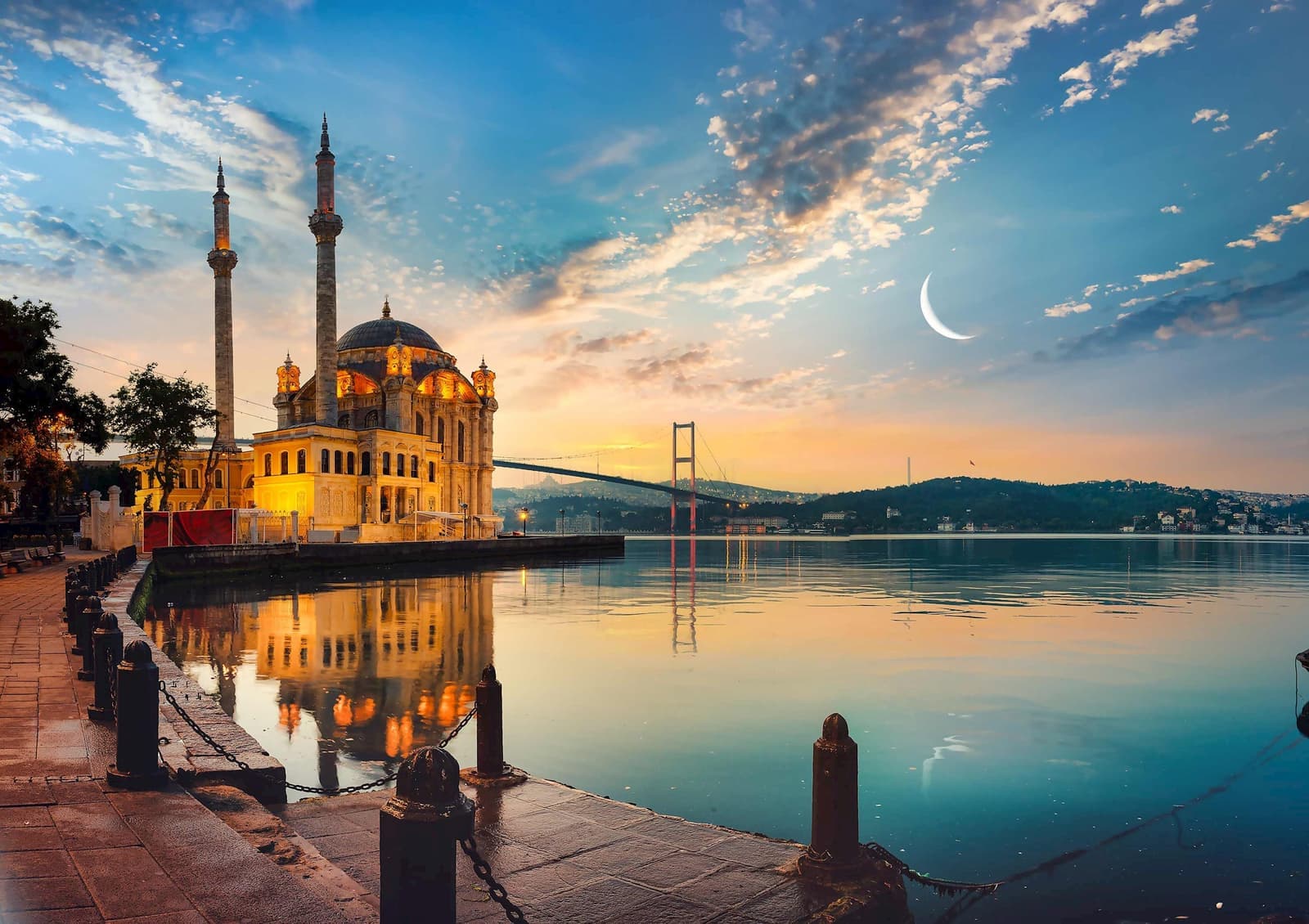 Waterside view with mosque and minarets and Bosphorus Bridge at sunset, Istanbul, Turkey