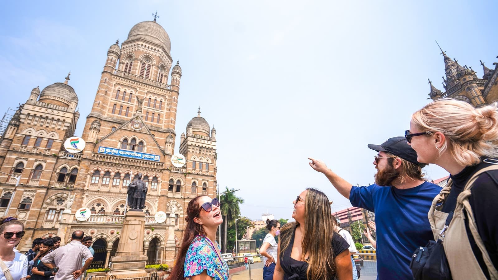 Group of travellers pointing up towards a local building in Mumbai, India