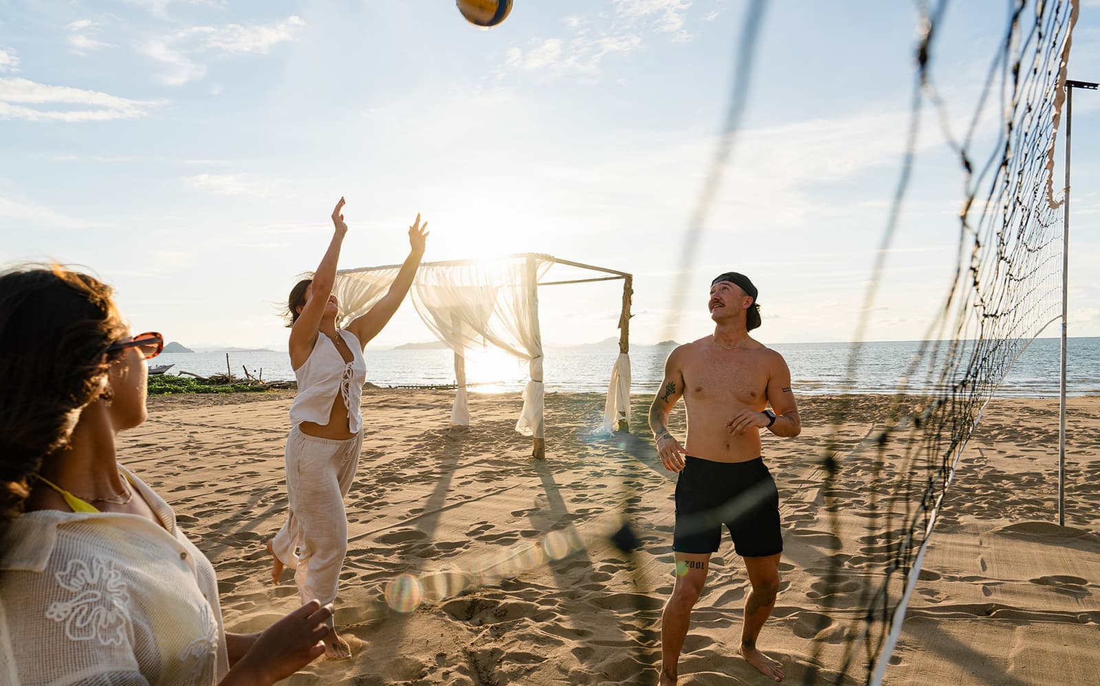 Three travellers playing volleyball on the beach in Labuan Bajo, Indonesia