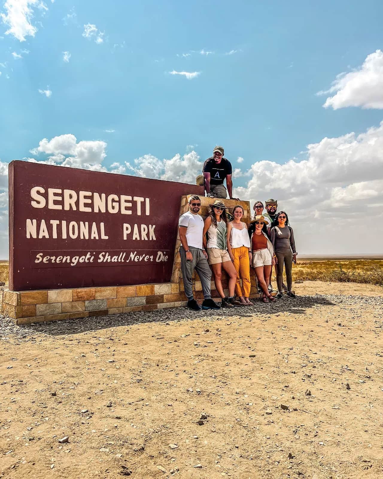 Group of travellers standing in front of the Serengeti National Park sign in the Serengeti, Tanzania