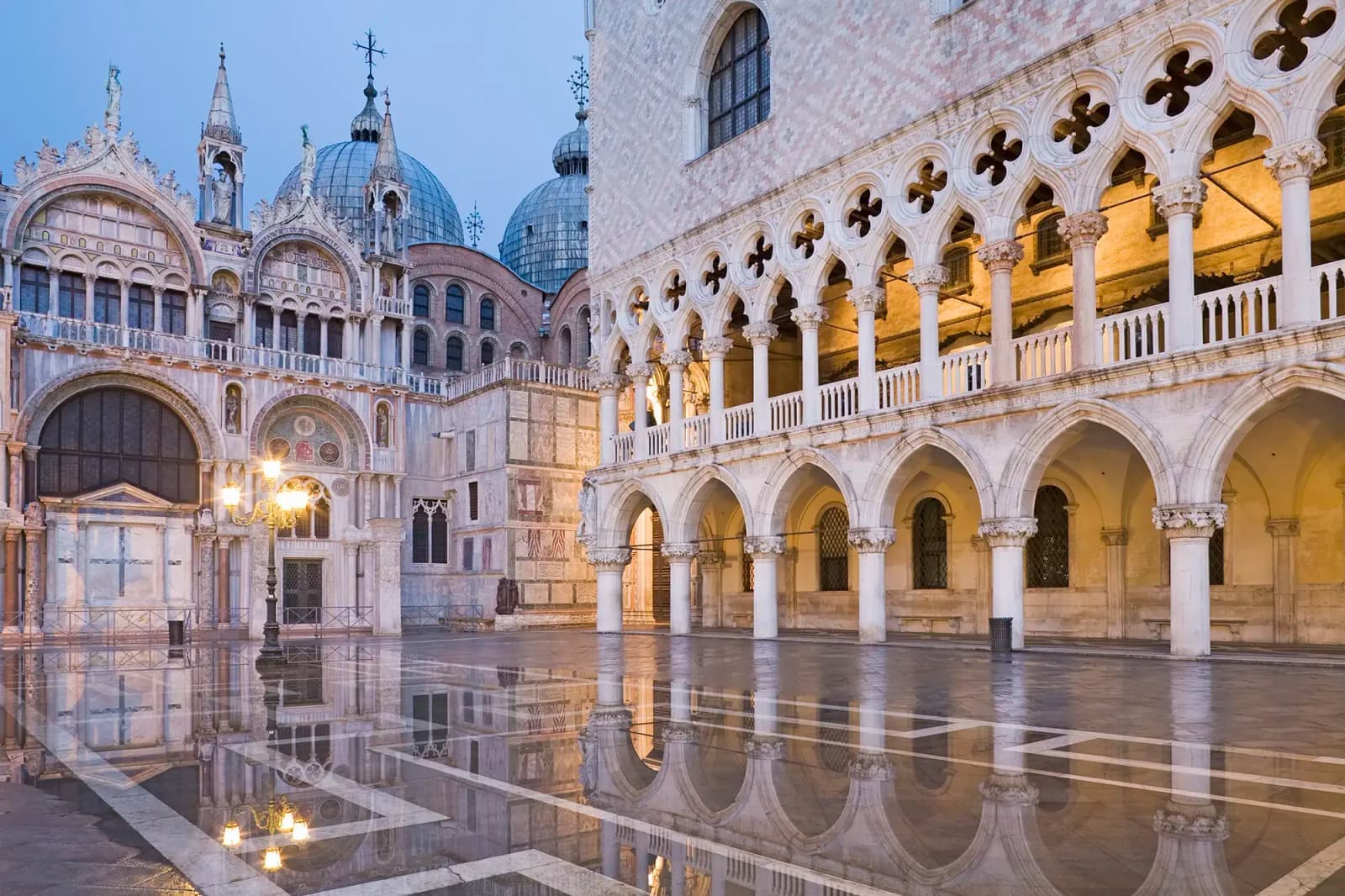 Doge's Palace and St. Mark's Basilica reflecting in wet pavement in Venice, Italy.