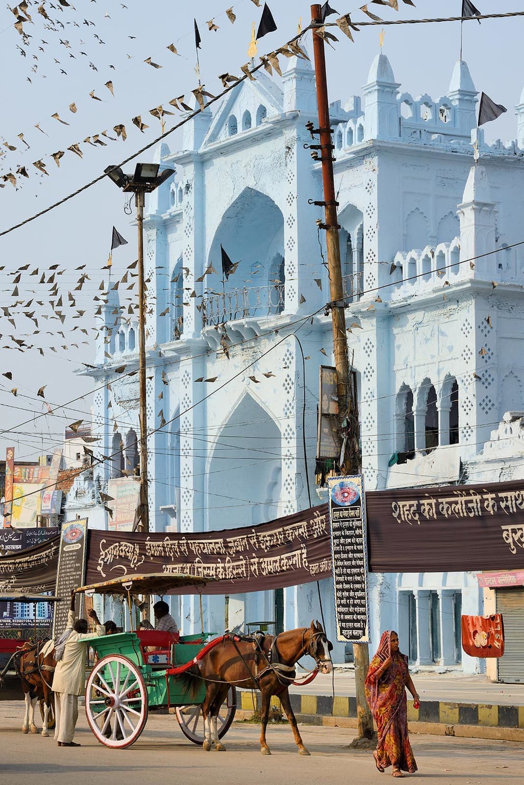 Ornate blue gate with horse-drawn carriage and pedestrians, Lucknow, India