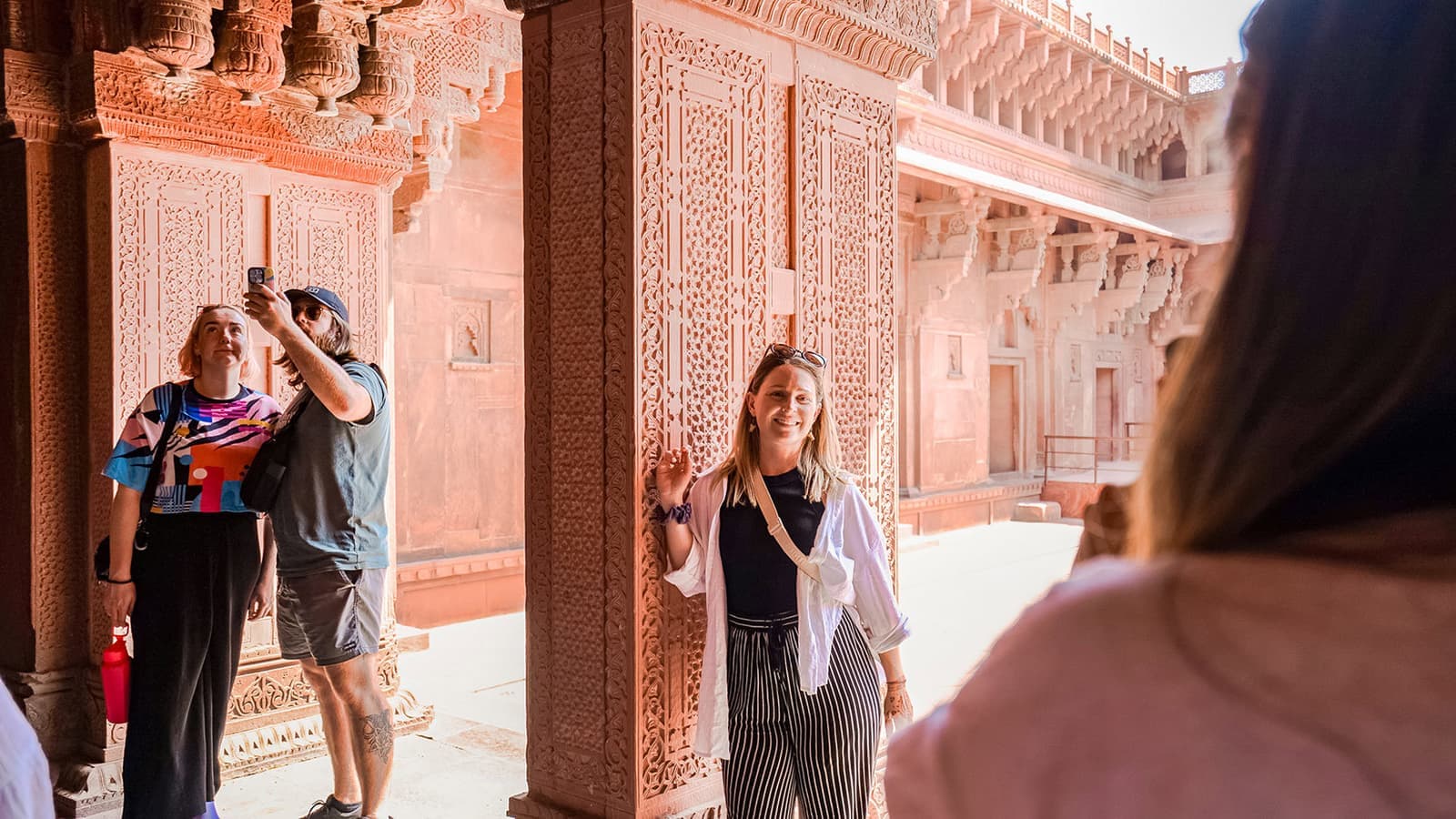 Travellers explore intricate red sandstone carvings at a fort, Jaipur, India