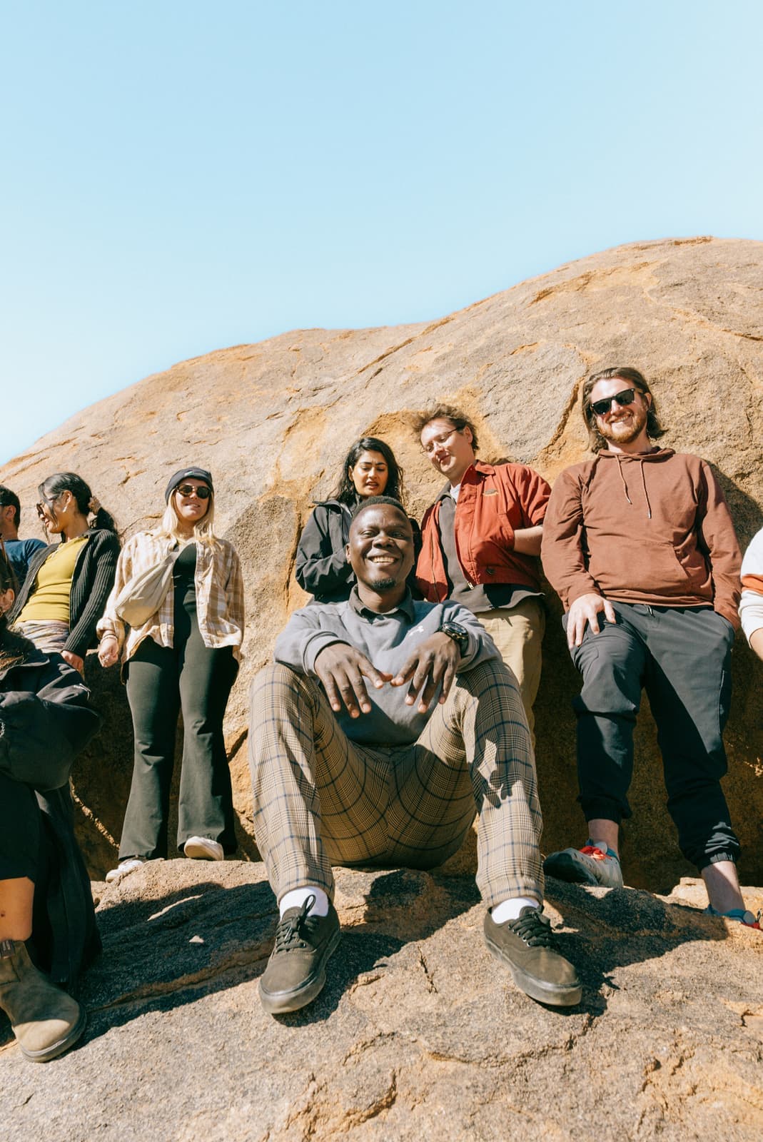 Travellers smiling at the camera standing and sitting on a rock