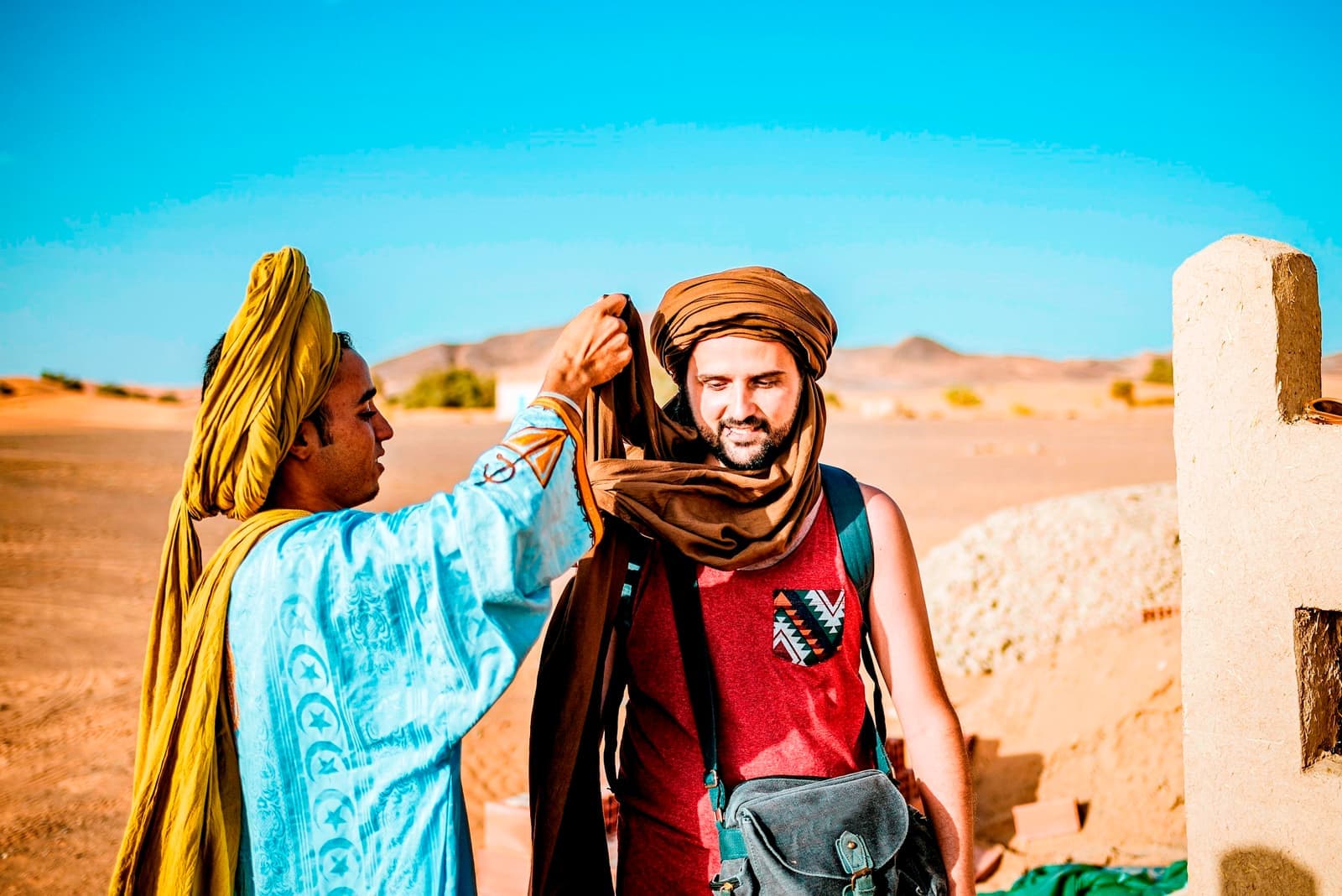 Berber guide helping a traveller wrap a turban in Merzouga, Morocco