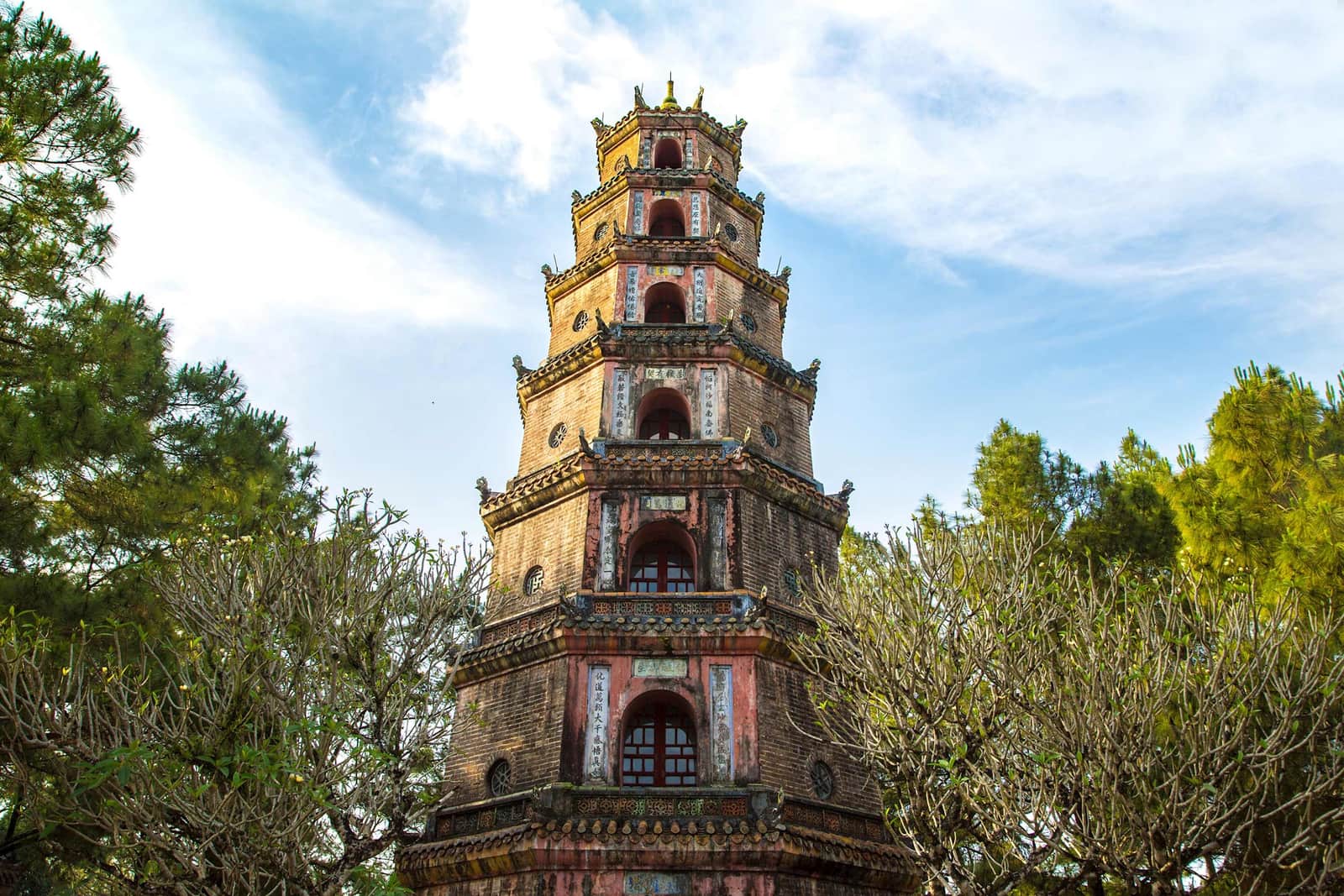Thien Mu Pagoda rising above trees under clear blue sky, Hue, Vietnam