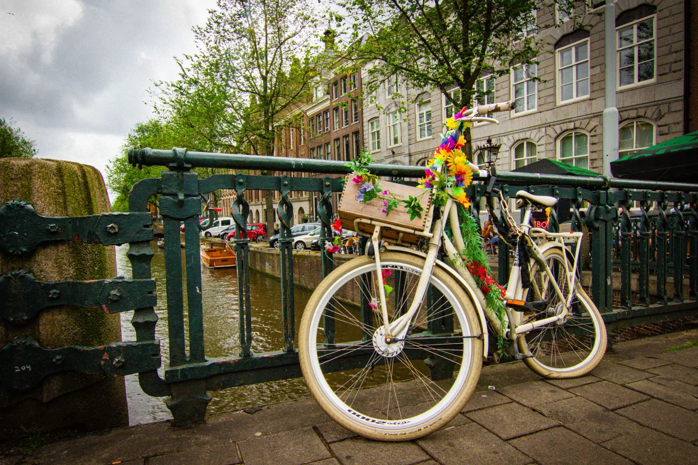 A flower-adorned bicycle rests against a bridge along Amsterdam's picturesque canals.