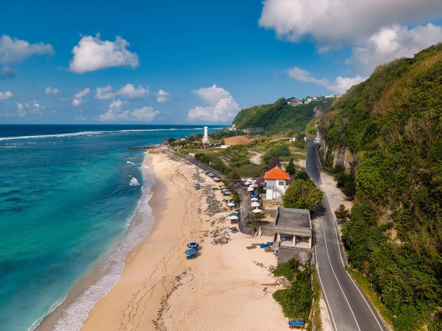 Aerial view of a Bali beach with a lighthouse and scenic coastline in Indonesia.