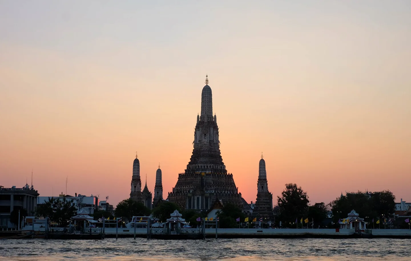 Beautiful sunset view of Wat Arun temple silhouetted against a colorful sky in Bangkok, Thailand.
